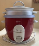 Oster 6-CUP Rice Cooker With Steamer, Red (004722-000-000). Fixed Price $22.99.
